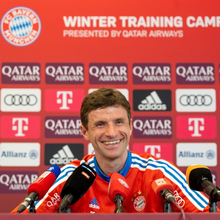 Thomas Müller lacht auf einer Pressekonferenz des FC Bayern München.