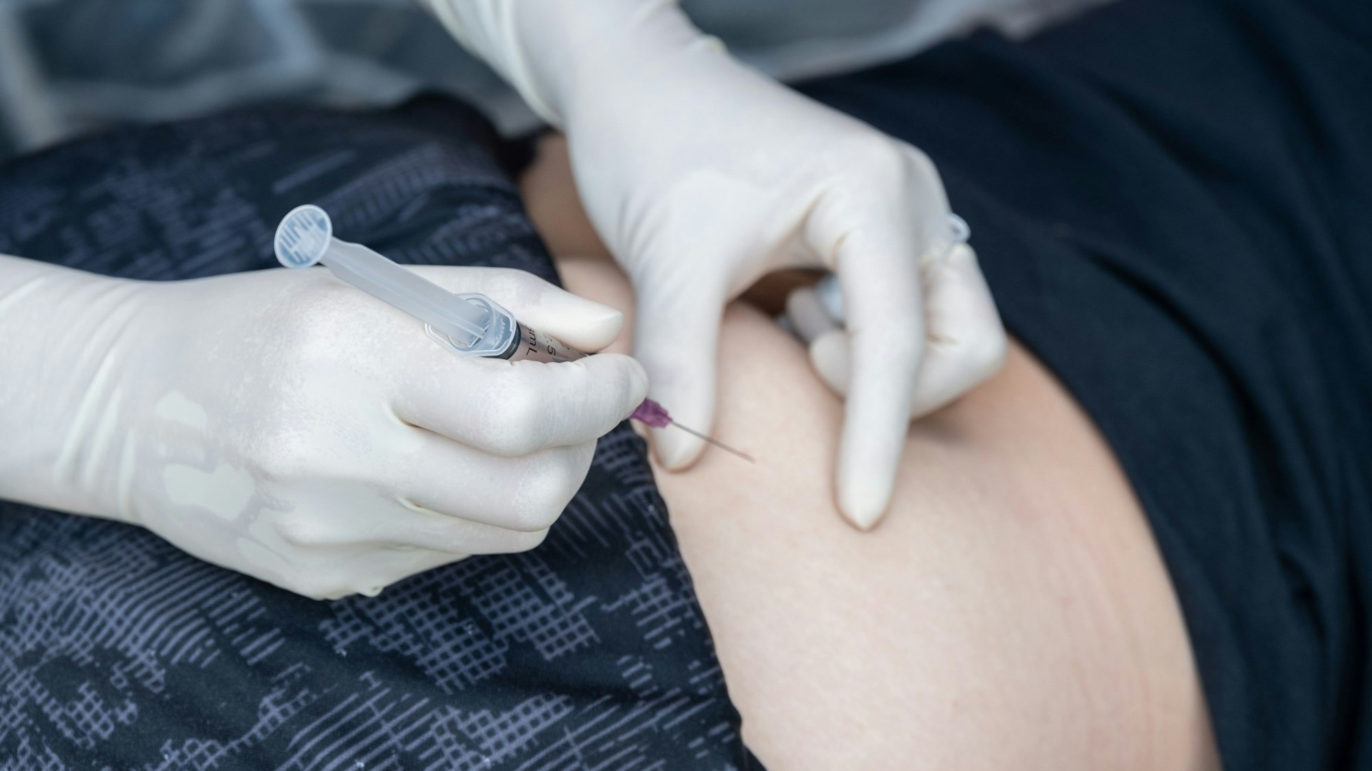 Nahaufnahme einer medizinischen Fachkraft, die dem Patienten eine intramuskuläre Injektion in den Gesäßmuskel gibt.