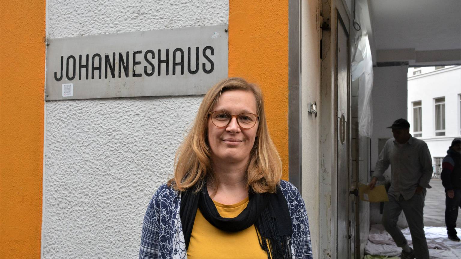 Die Leiterin des Johanneshauses vor einem Schild mit der Aufschrift: Johanneshaus.