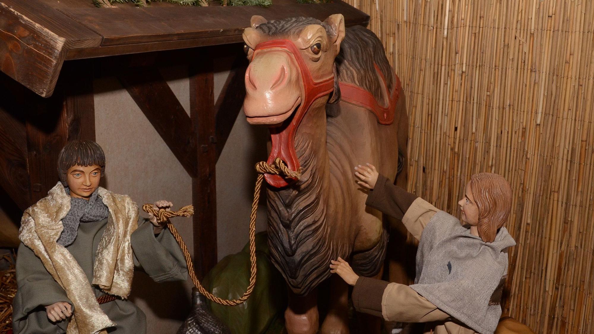 2 Hirtenfiguren mit einem Kamel vor dem Stall.