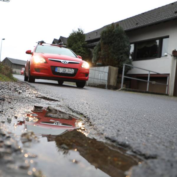 Ein Auto fährt auf einer Straße und spiegelt sich in einer Pfütze.