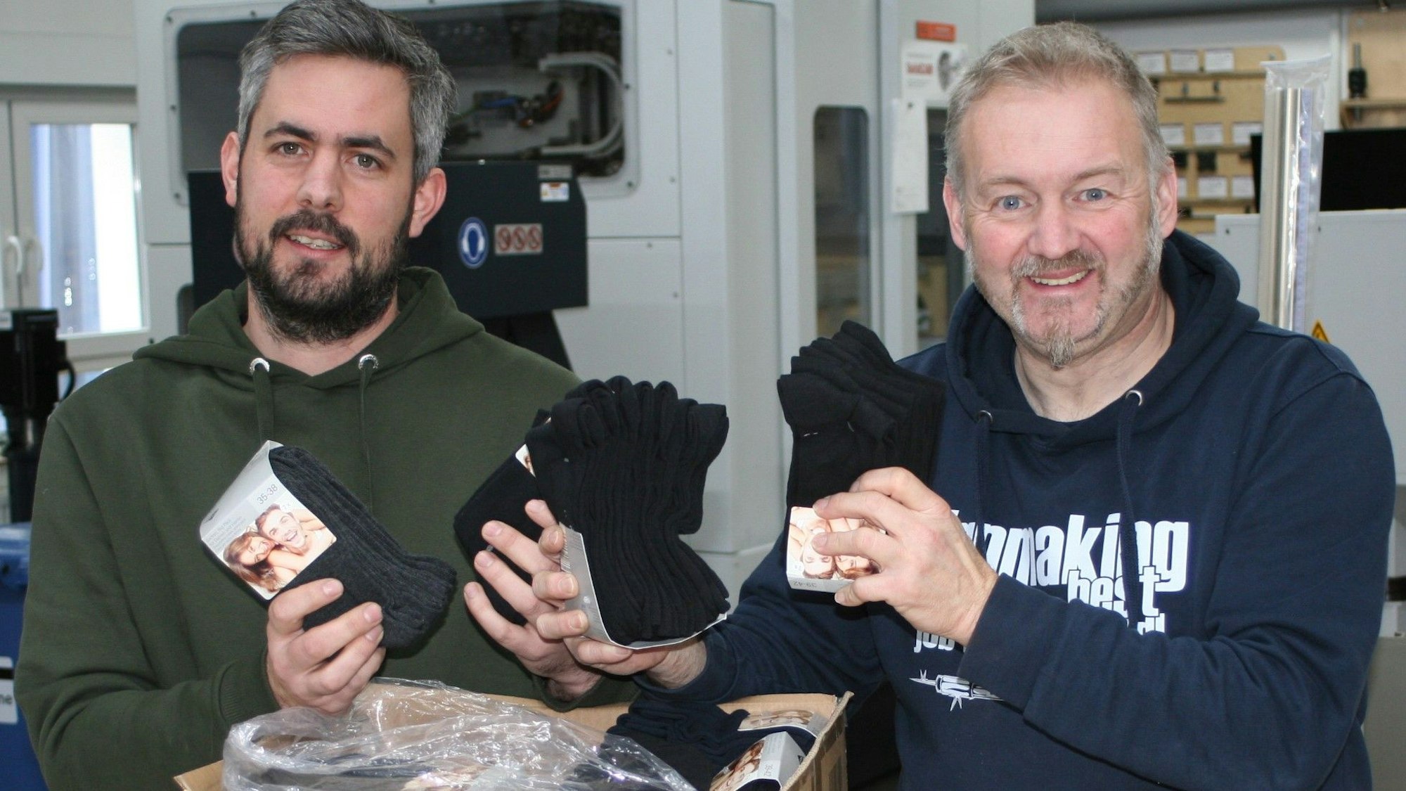 Michael Althoff (r.) und ein weiterer Mann zeigen die Socken für die Spendenaktion.