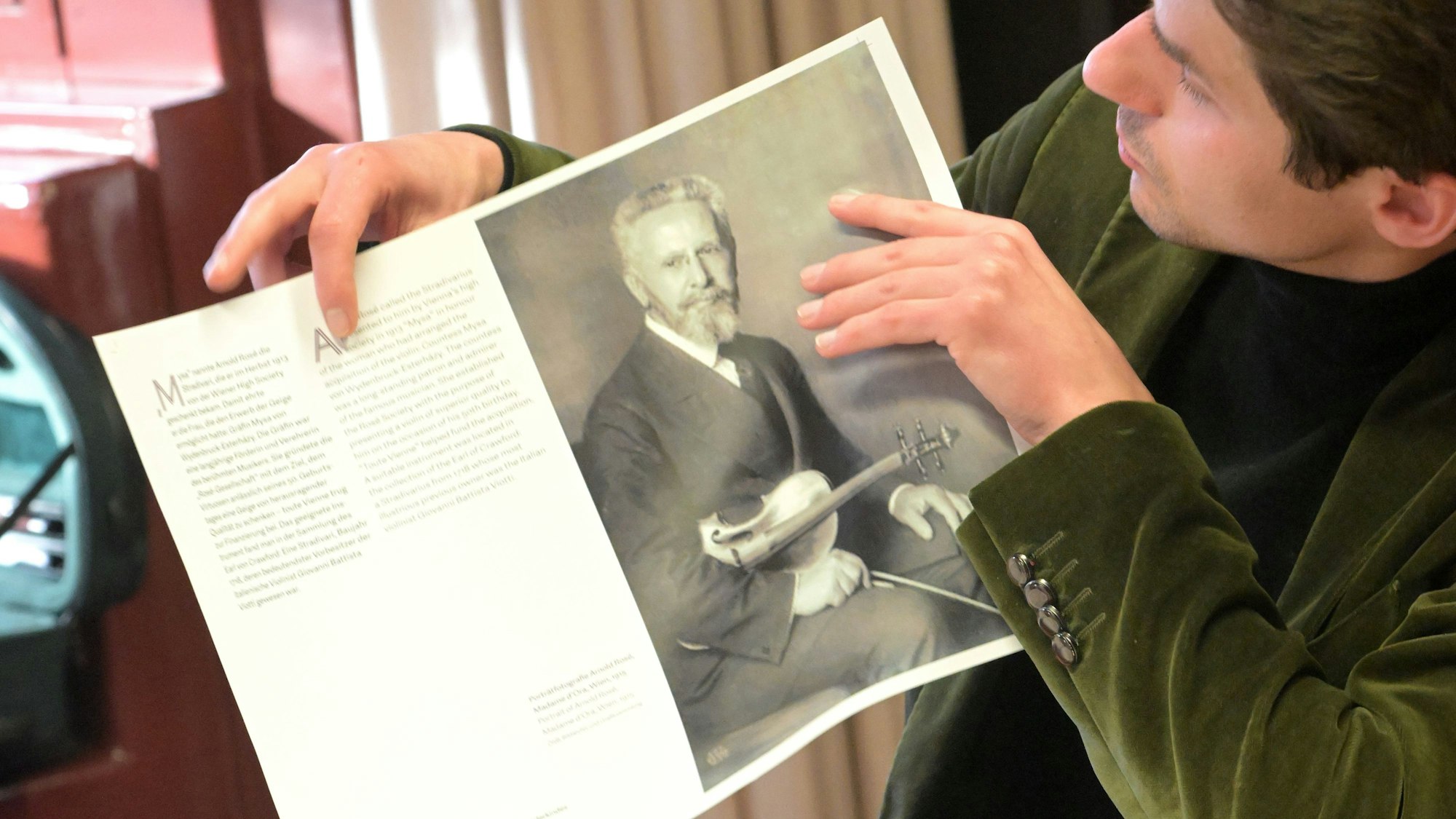 Roman Salyutov zeigt ein Plakat, das in der Ausstellung zu sehen sein wird.