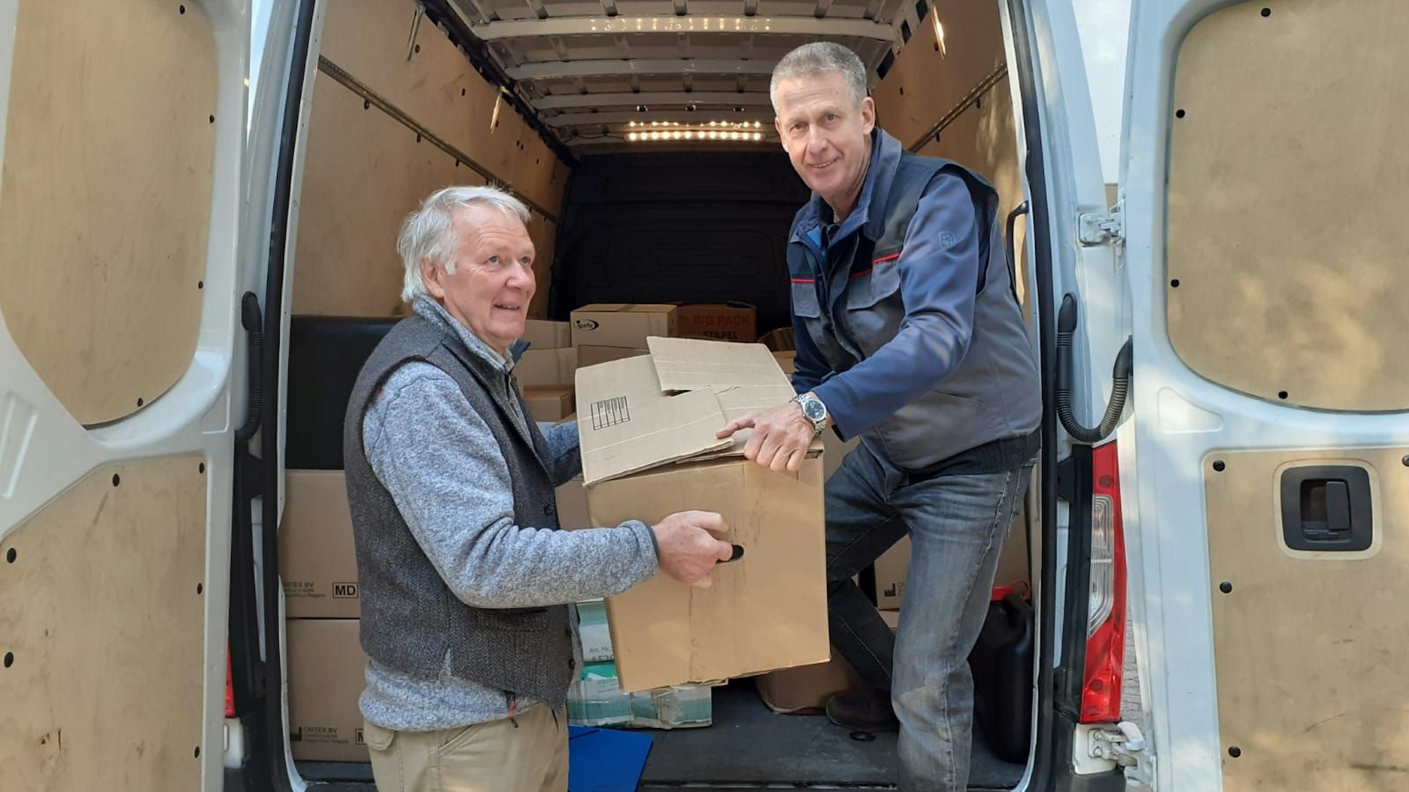 Wilhelm Stein (l.) und Ferdi Schwanitz verladen Kartons in einen Sprinter.
