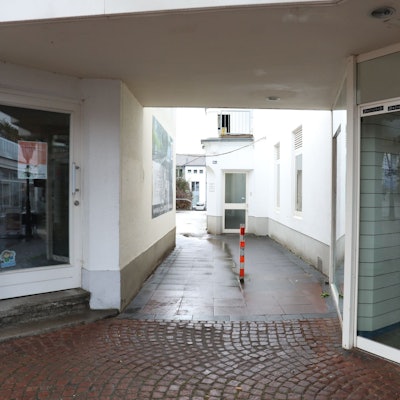 Ein schmaler Durchgang führt zwischen zwei Ladenlokalen hindurch.