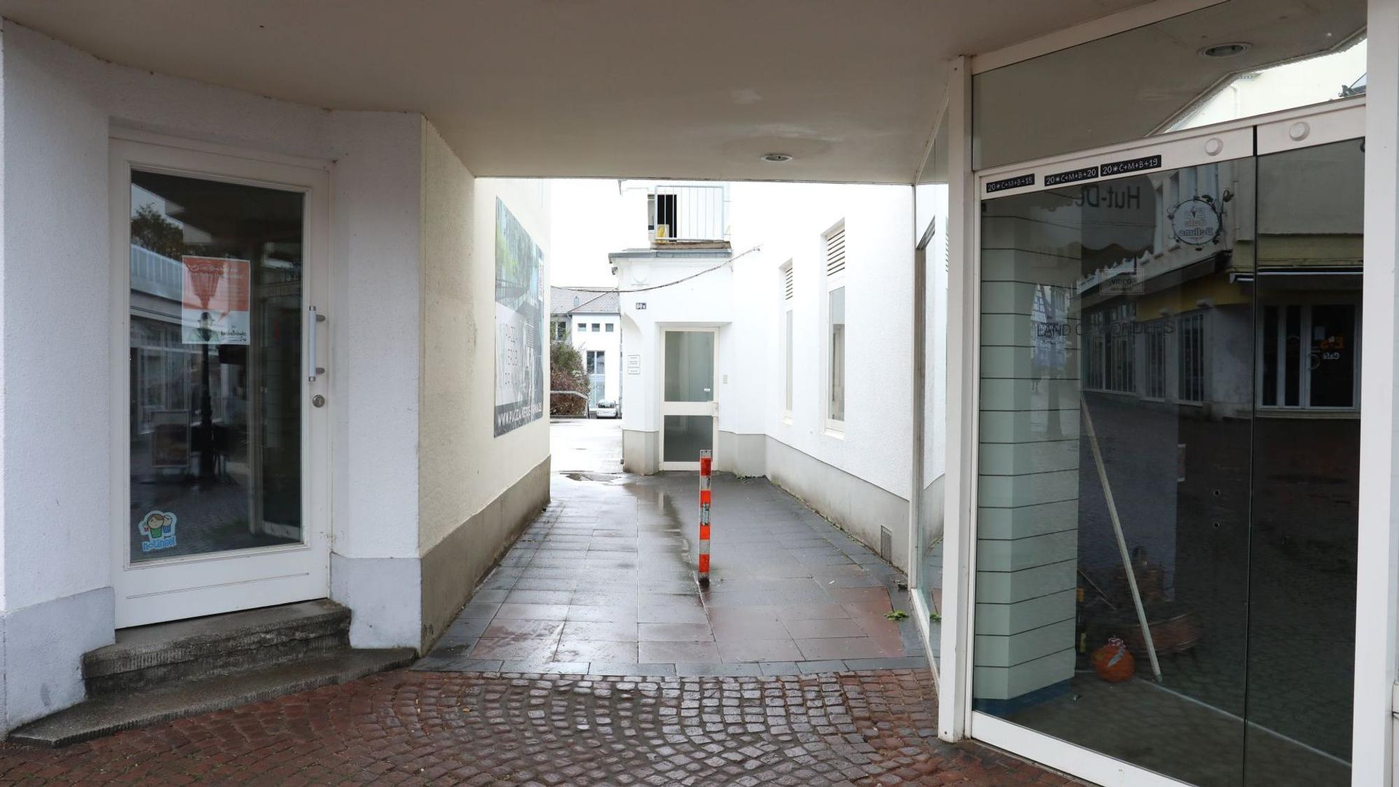 Ein schmaler Durchgang führt zwischen zwei Ladenlokalen hindurch.