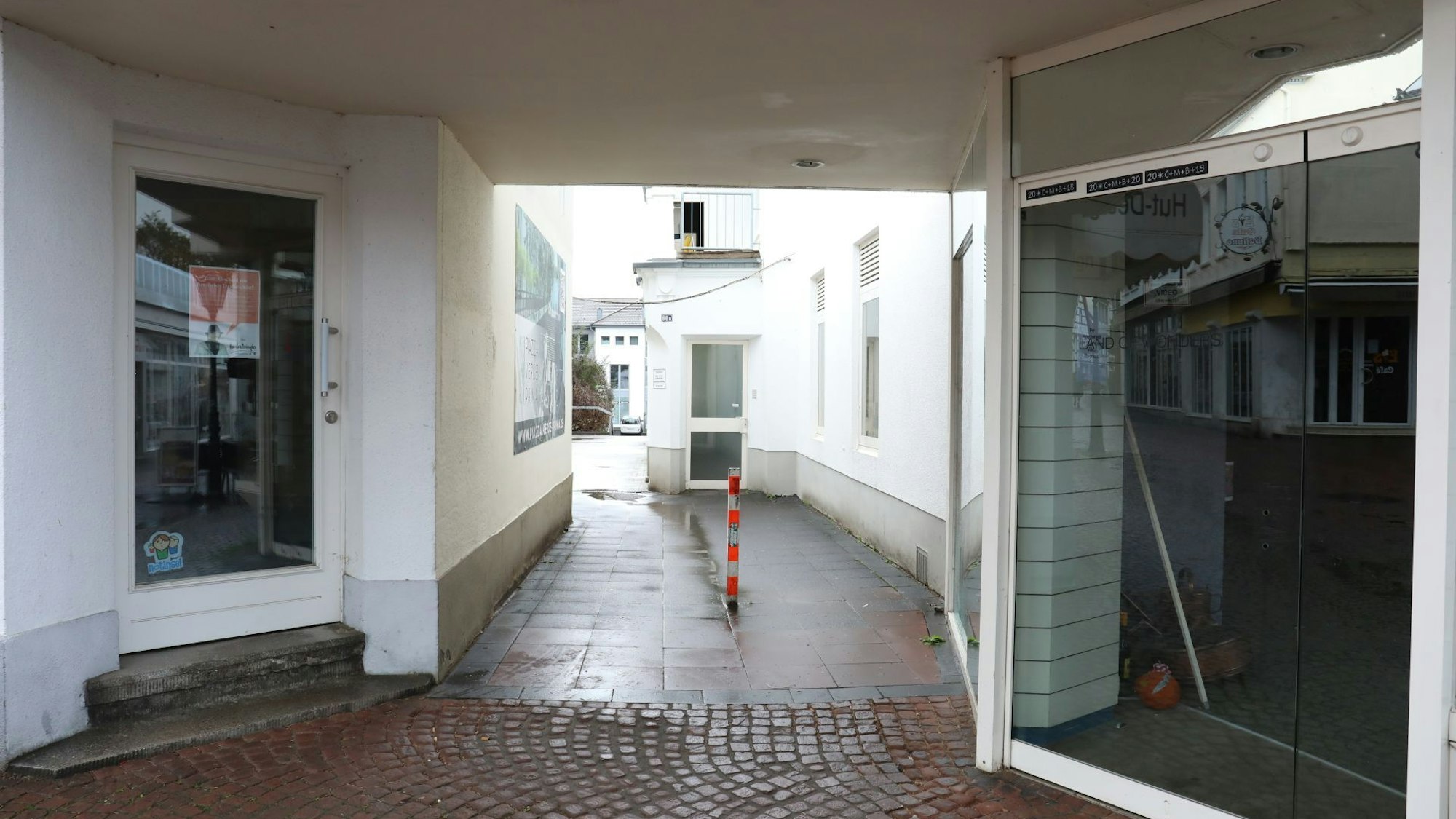 Ein schmaler Durchgang führt zwischen zwei Ladenlokalen hindurch.