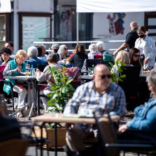 In die Euskirchener Innenstadt, hier einige Personen an Tischen der Außengastronomie im März 2022, kehrt das Leben zurück. Doch es ist noch viel Aufbauarbeit nötig.