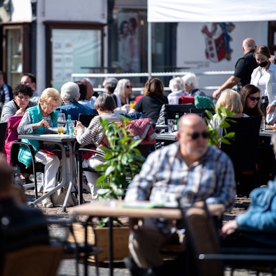 In die Euskirchener Innenstadt, hier einige Personen an Tischen der Außengastronomie im März 2022, kehrt das Leben zurück. Doch es ist noch viel Aufbauarbeit nötig.