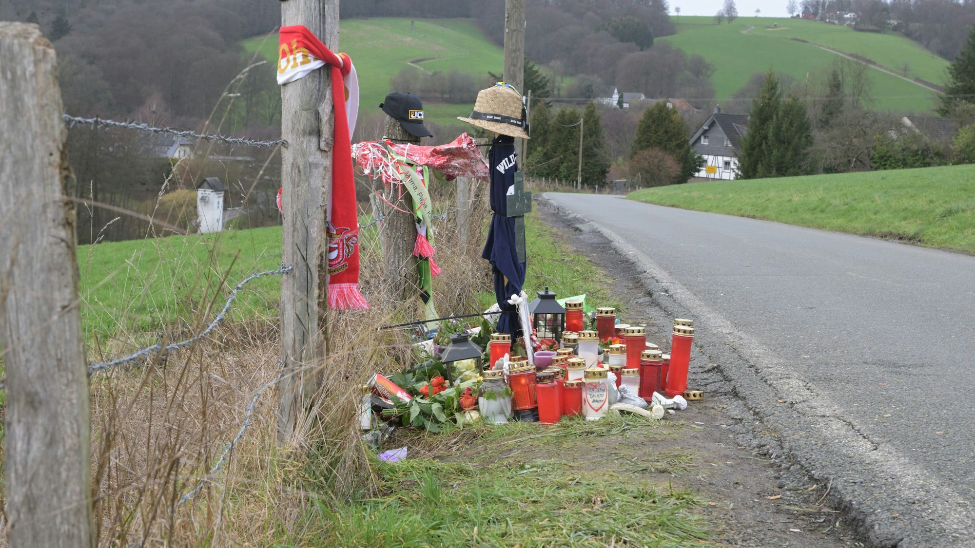 Grablichter und Andenken stehen neben einer Straße.