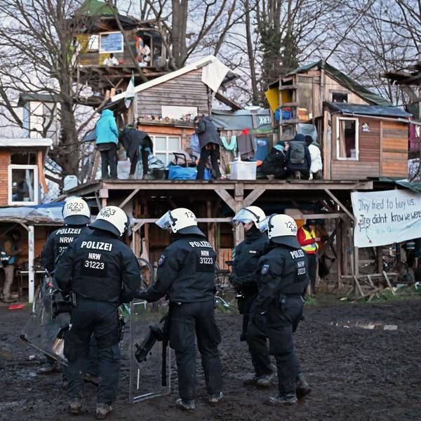 Polizisten stehen bei der Räumung von Lützerath vor Bretterhütten.