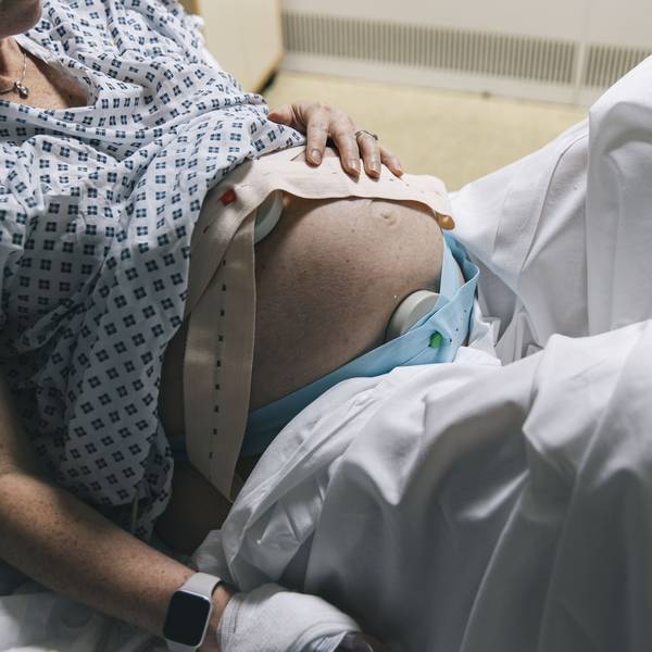 Eine unkenntliche, schwangere Frau liegt in einem Krankenhausbett.