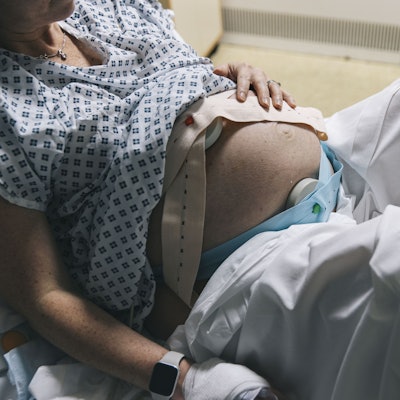 Eine unkenntliche, schwangere Frau liegt in einem Krankenhausbett.