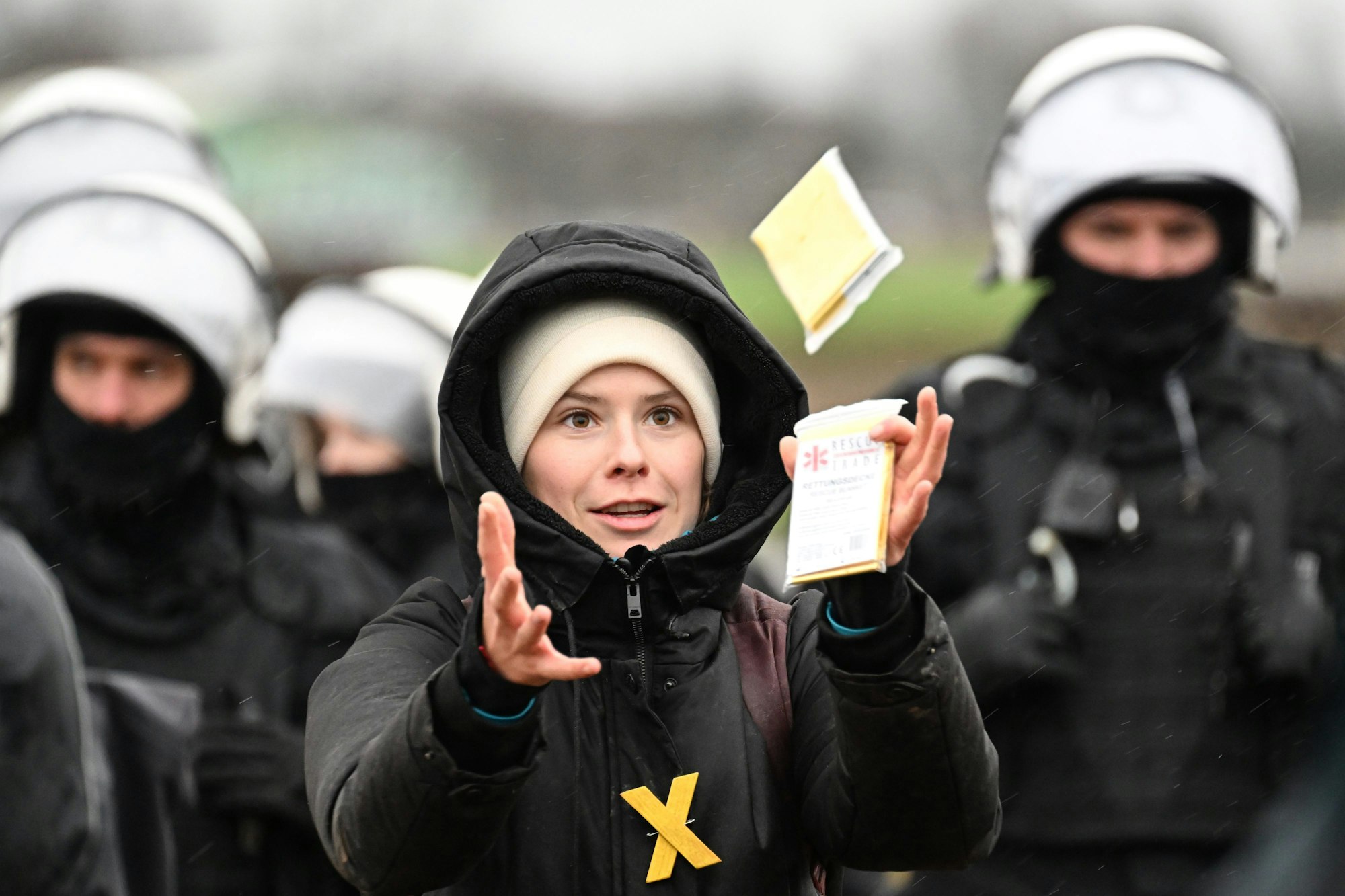 12.01.2023, Nordrhein-Westfalen, Erkelenz: Umweltaktivistin Luisa Neubauer fängt eine eingepackte Rettungsdecke, als sie bei einer Sitzblockade vor einer Reihe von Polizisten steht. Die Demonstranten hatten versucht am zweiten Tag der Räumung durch die Polizei über Äcker zum besetzten Braunkohleort Lützerath zu gelangen und wurden von der Polizei gestoppt.