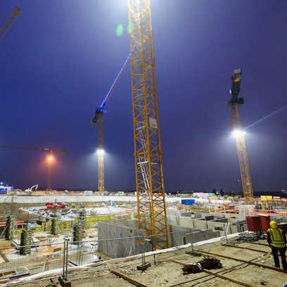Kräne ragen über das Neubaugebiet Kronsrode in Hannover auf der Baustelle eines Mehrfamilienhauses.