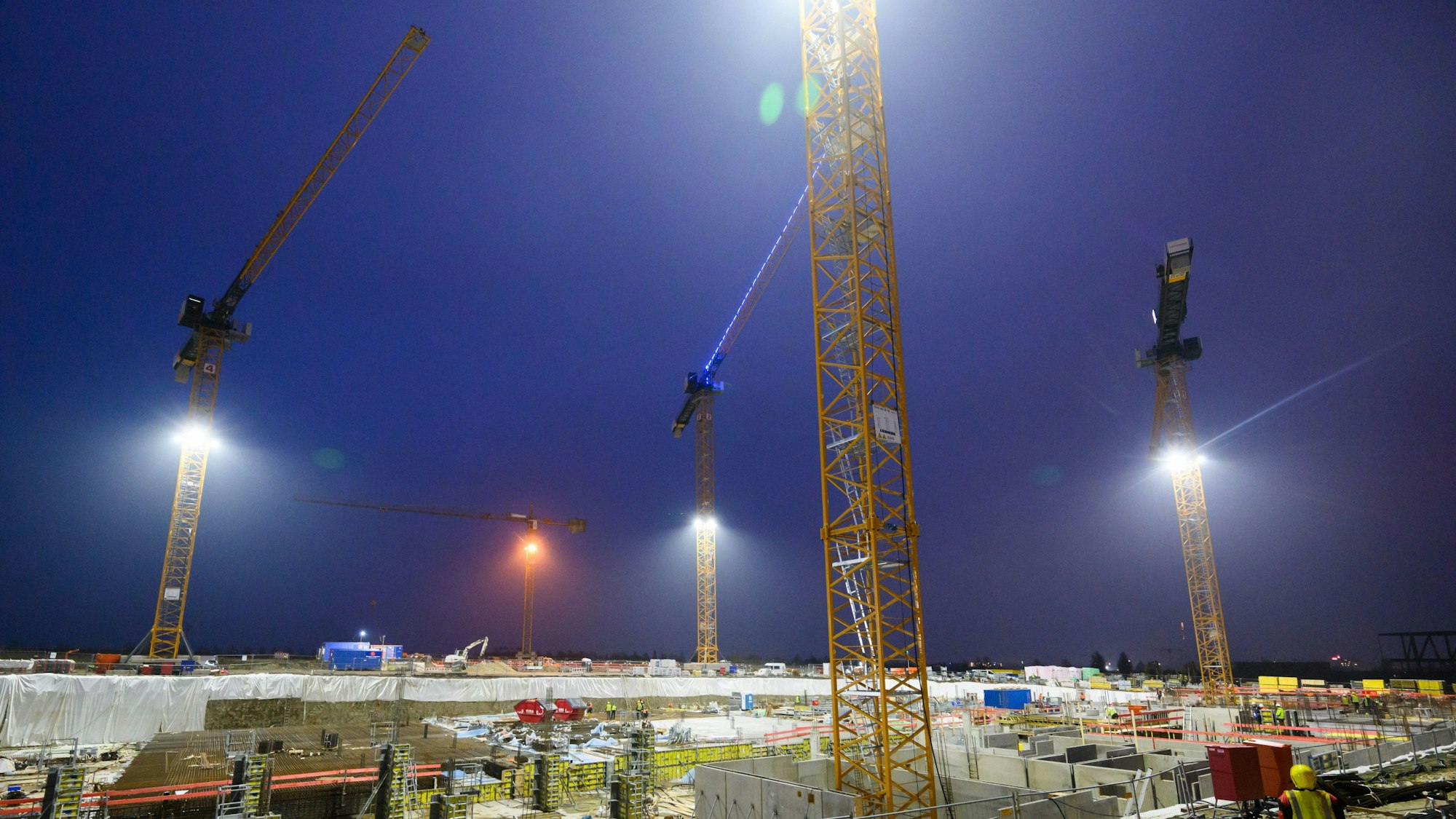 Kräne ragen über das Neubaugebiet Kronsrode in Hannover auf der Baustelle eines Mehrfamilienhauses.
