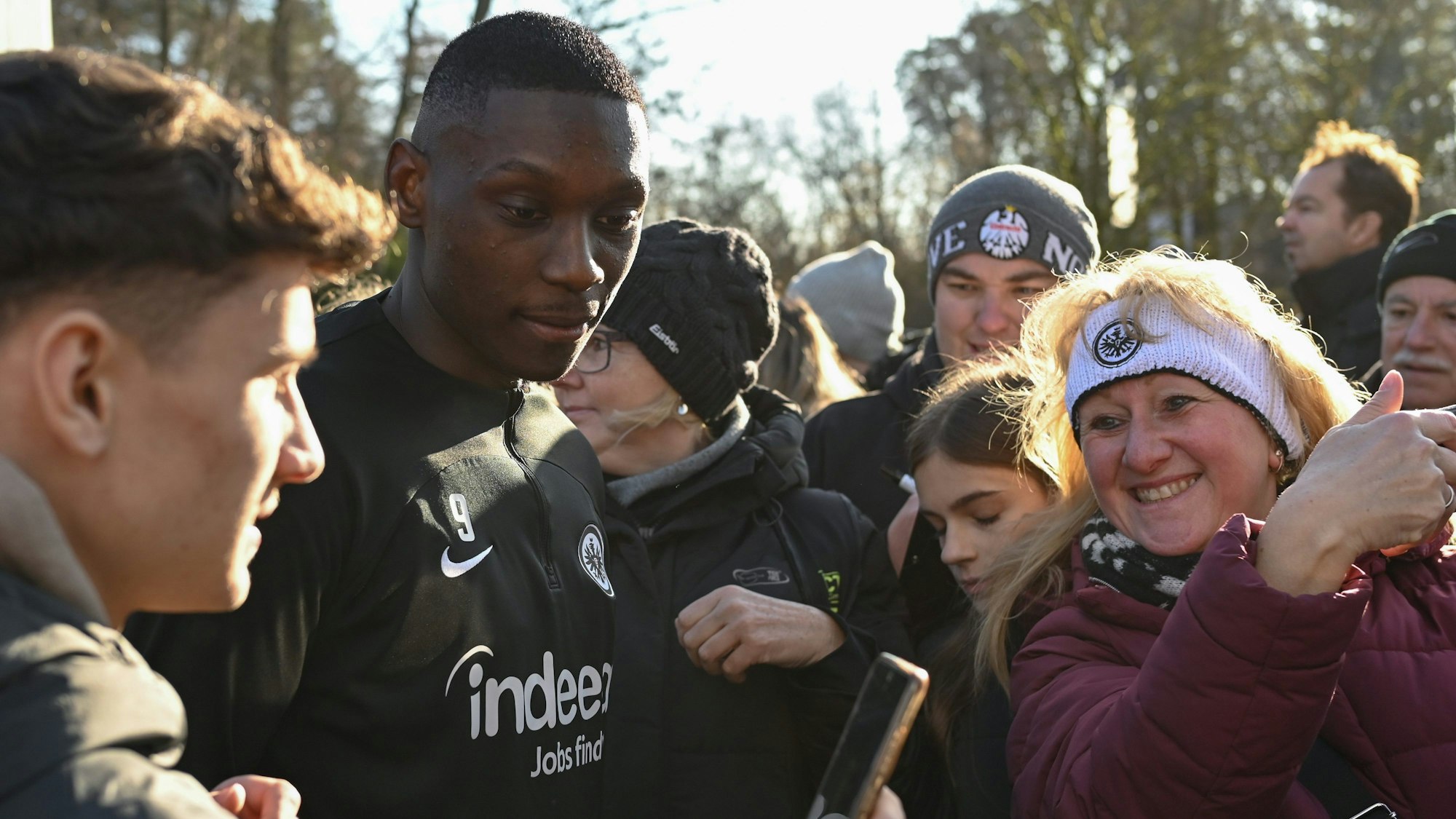 Frankfurts Stürmer Randal Kolo Muani (2.v.l.) ist nach dem Trainingsauftakt von Fans umringt.