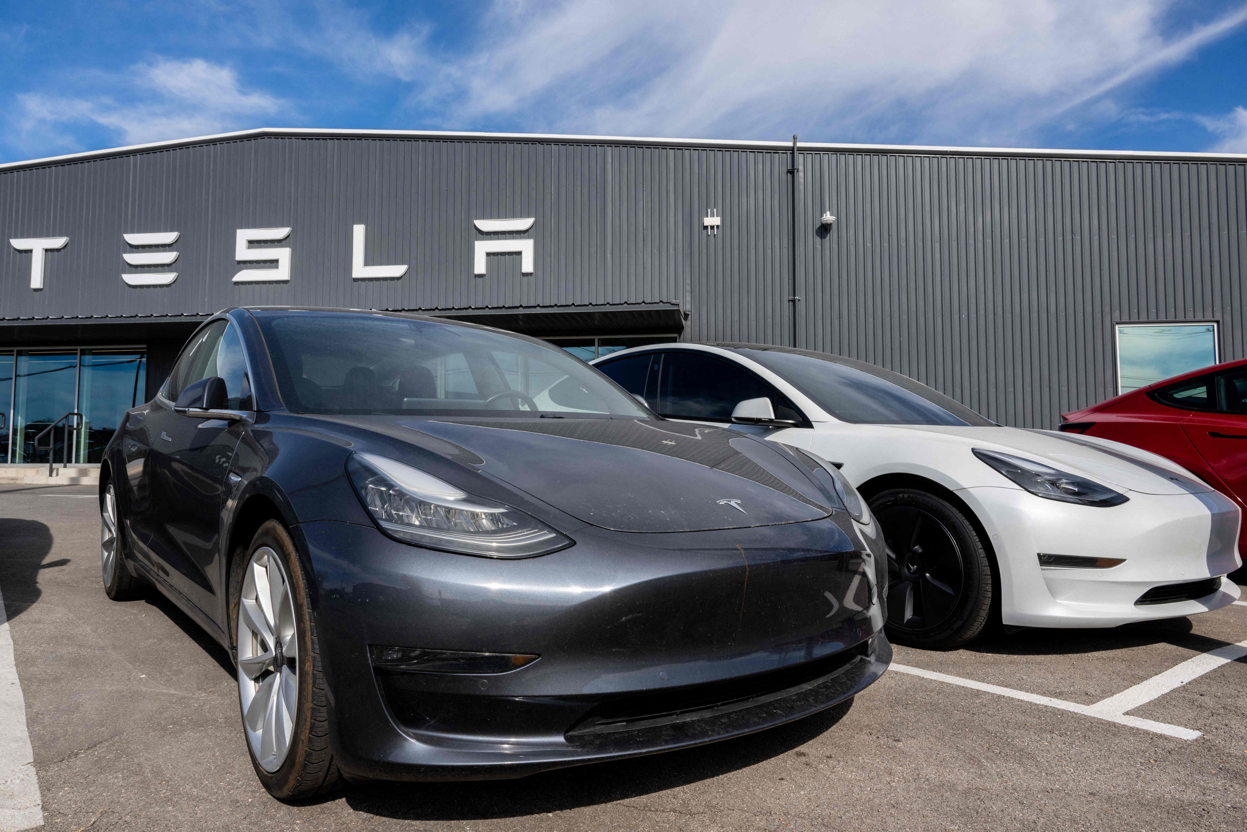 Autos von Tesla stehen vor einem Autohaus von Tesla.