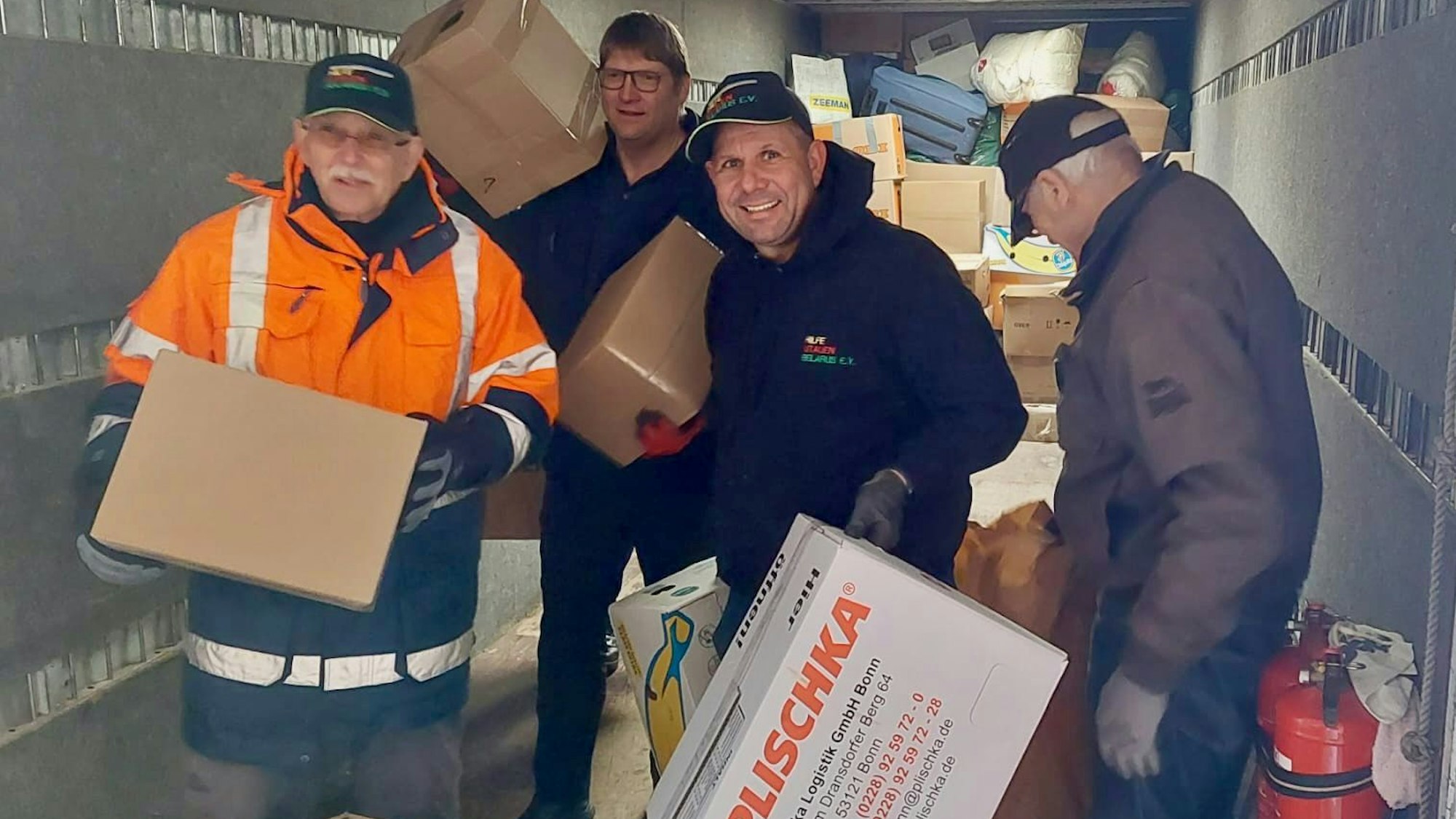 Vier Männer laden Kartons in einen Lastwagen.