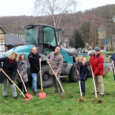 Mit Spaten wird erste Erde auf der Wiesenfläche ausgehoben.