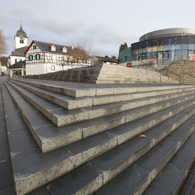 Eine Treppenanlage führt auf das runde Gebäude zu, das bis Ende Dezember das Sealife-Aquarium beherbergte. Im Hintergrund links ist der Turm der Pfarrkirche St-Remigius zu sehen..