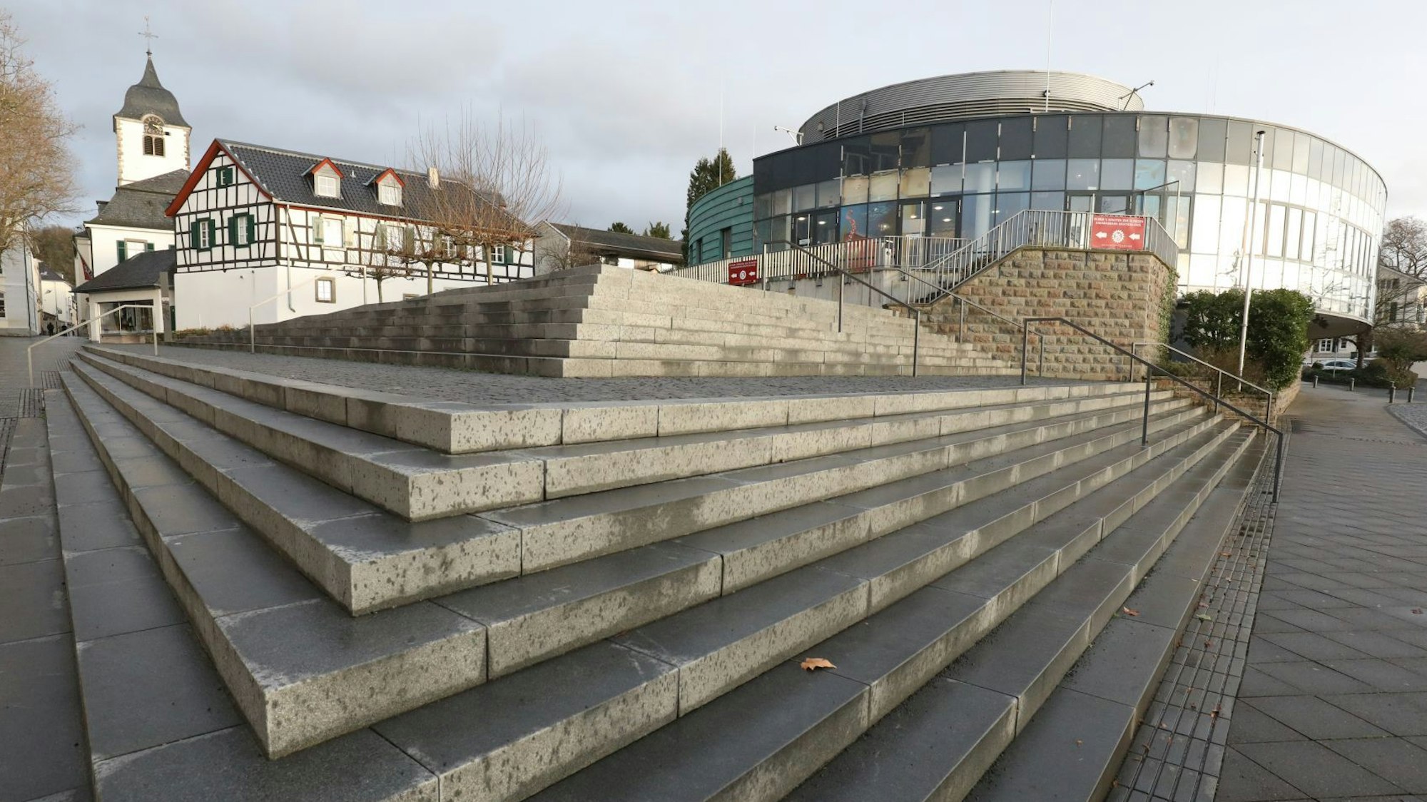 Eine breite Treppenanlage führt zu einem ovalen Gebäude mit einer Glasfront.