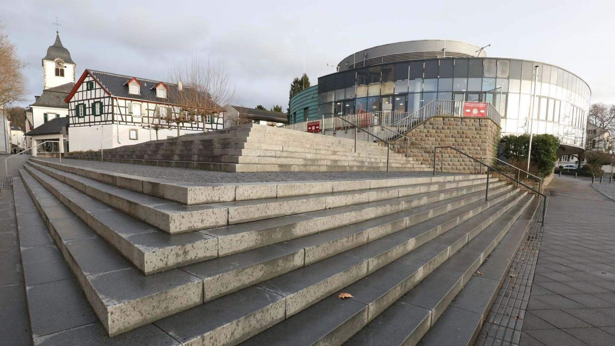 Treppenstufen führen zum ehemaligen Sealife-Gebäude, im Hintergrund steht die Pfarrkirche St. Remigius.