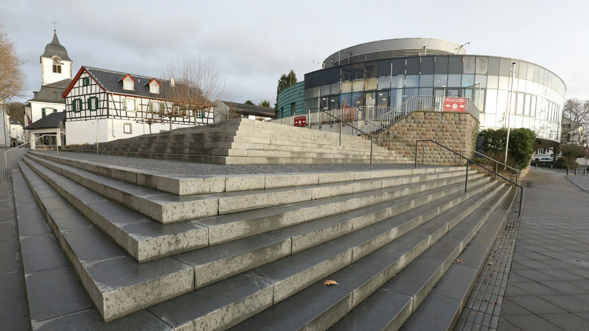 Treppenstufen führen zum ehemaligen Sealife-Gebäude, im Hintergrund steht die Pfarrkirche St. Remigius.