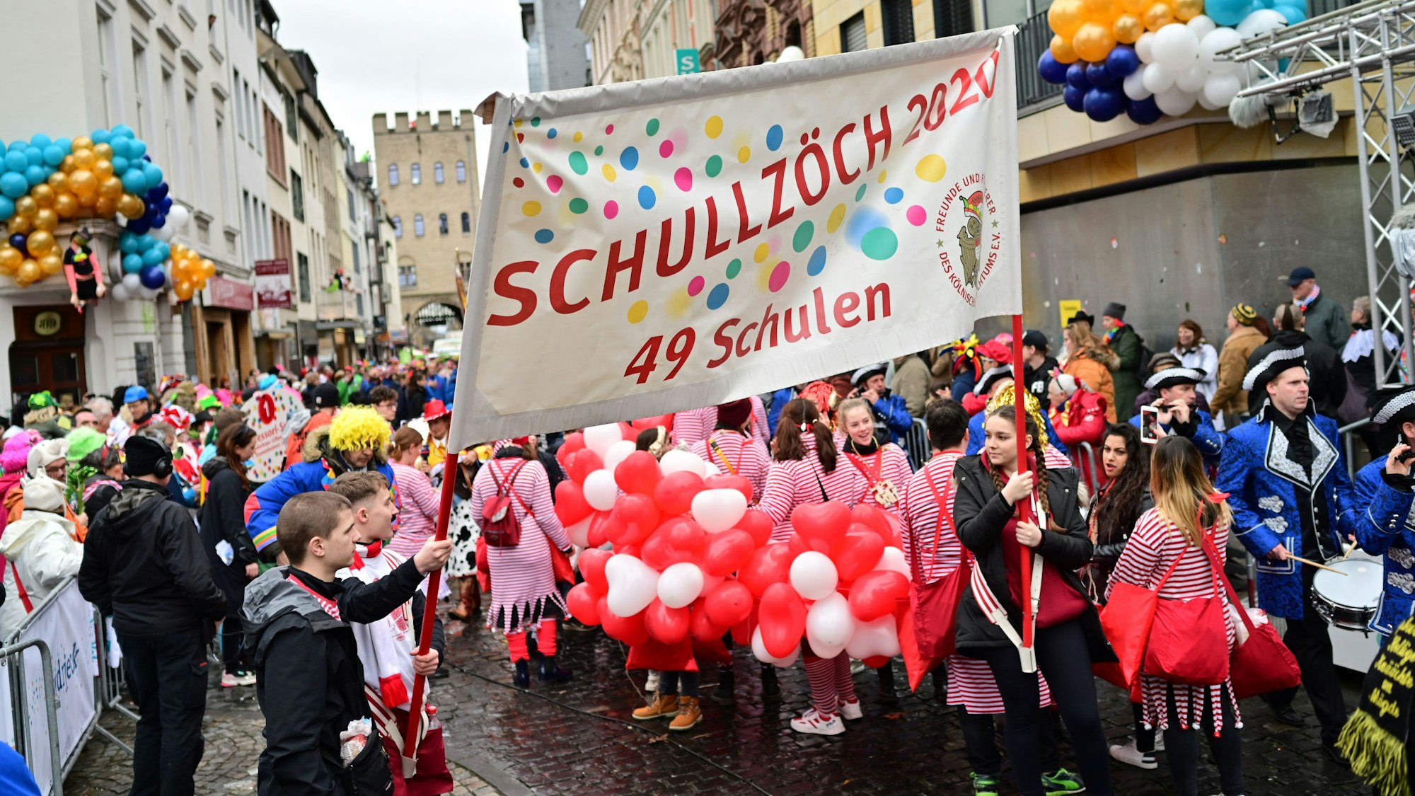 Im ersten Zug nach der Pandemie werden am Karnevalssonntag deutlich weniger Teilnehmende bei den Schull- un Veedelszöch mitgehen. Schüler halten ein Transparent mit der Beschriftung "Schullzöch 2020 - 49 Schulen".