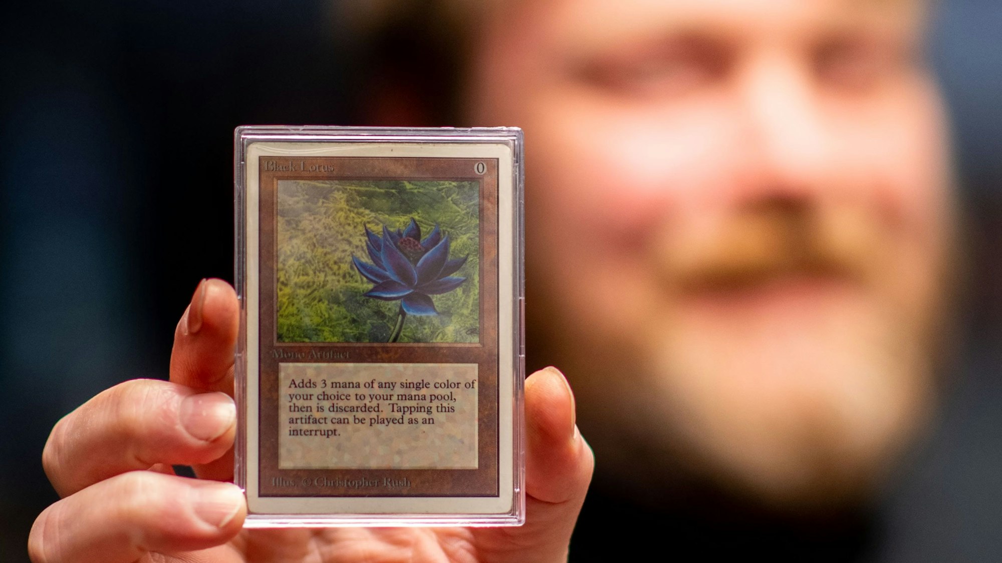 Der Besitzer des Fantasy Store in Euskirchen hält eine seltene Spielkarte in der Hand.