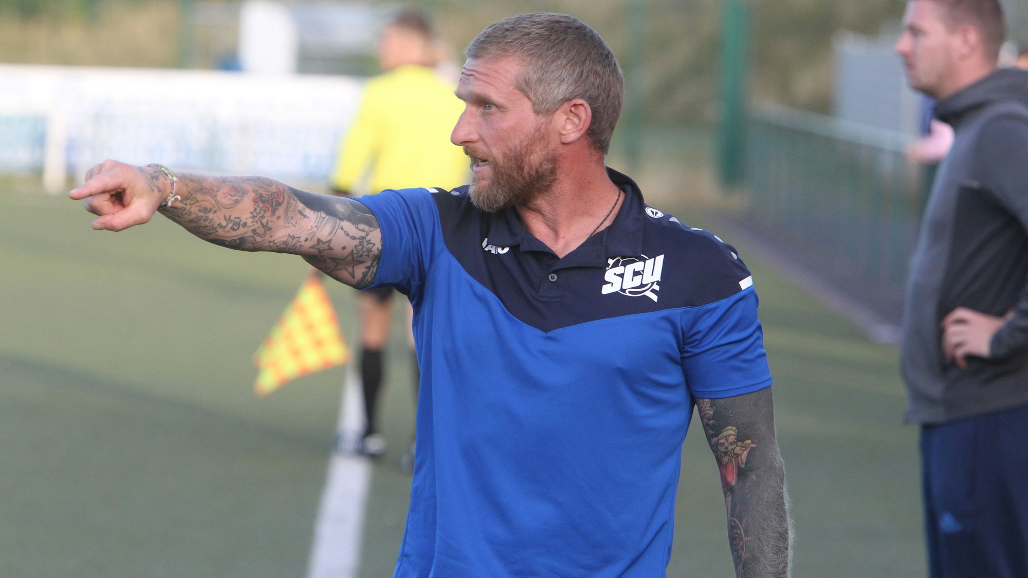 Trainer Didi Rombach vom SC Uckerath zeigt mit ausgestreckten Arm und Zeigefinger aufs Spielfeld.