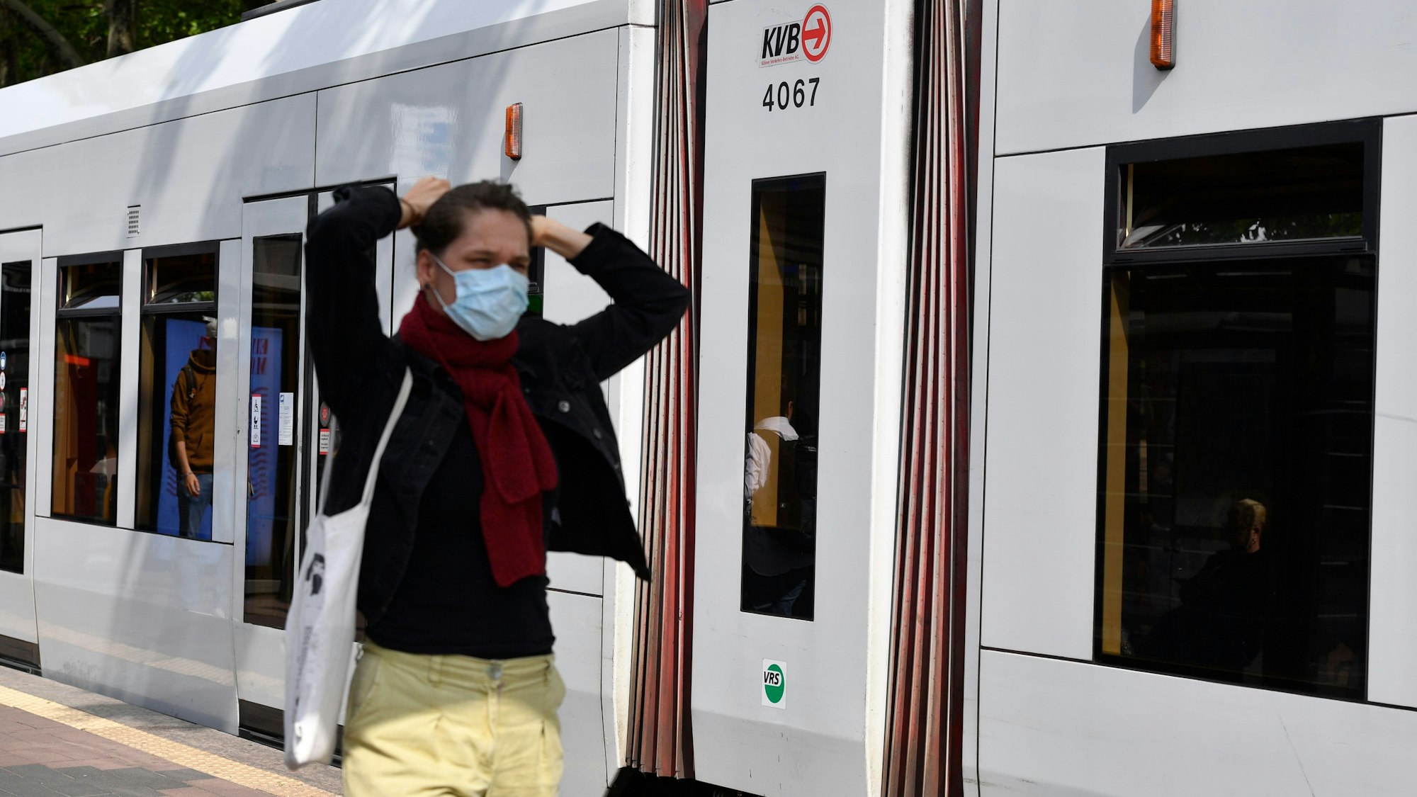 26.05.2022, Nordrhein-Westfalen, Köln: Eine Bürgerin trägt vor einer Straßenbahn Mund-Nasen-Schutz. Die heute in Kraft getretene neue Corona-Schutzverordnung ist die alte: Sie wurde nicht verändert und schlicht verlängert. Damit ändert sich auch an den Maßnahmen nichts. Und die Maskenpflicht im Öffentlichen Nahverkehr von Nordrhein-Westfalen wird bis kurz vor Beginn der Sommerferien verlängert. Foto: Roberto Pfeil/dpa +++ dpa-Bildfunk +++
