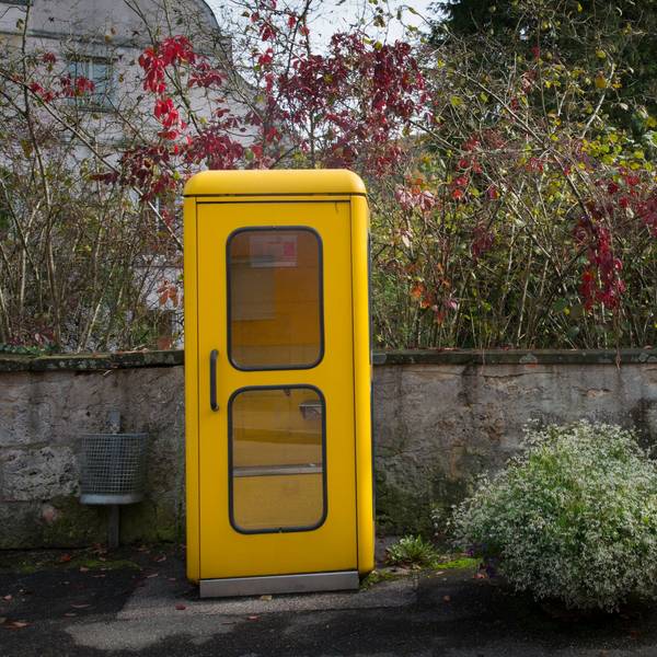 Eine gelbe Telefonzelle steht am Rande einer Straße.