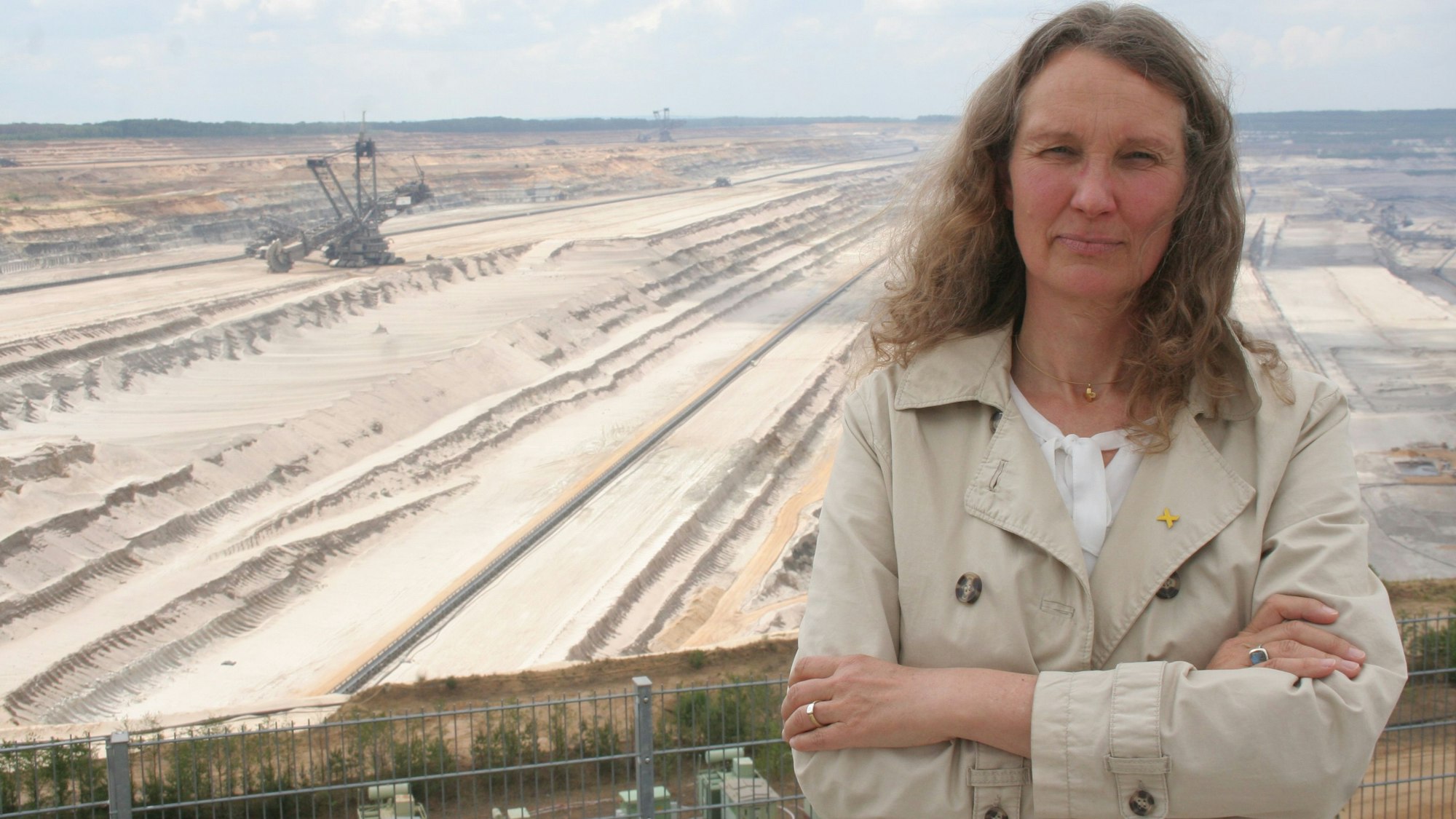 Antje Grothus steht vor dem Tagebau Hambach im Forum Terra Nova. Im Hintergrund ist ein Braunkohlebagger zu sehen. Das Foto entstand 2020.