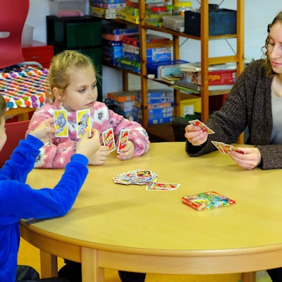 Sprachpatin Elisa Schmitz und ihre beiden Schützlinge aus der Grundschule in Hellenthal-Reifferscheid spielen eine Partie UNO.