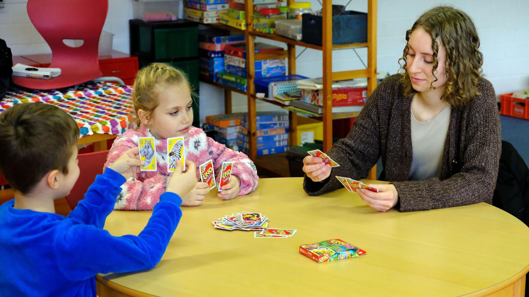 Sprachpatin Elisa Schmitz und ihre beiden Schützlinge aus der Grundschule in Hellenthal-Reifferscheid spielen eine Partie UNO.