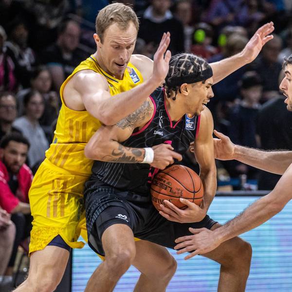 Zwei Basketballer in gelben Trainingsanzügen versuchen einem gegenerischen Spieler den Ball abzunehmen.