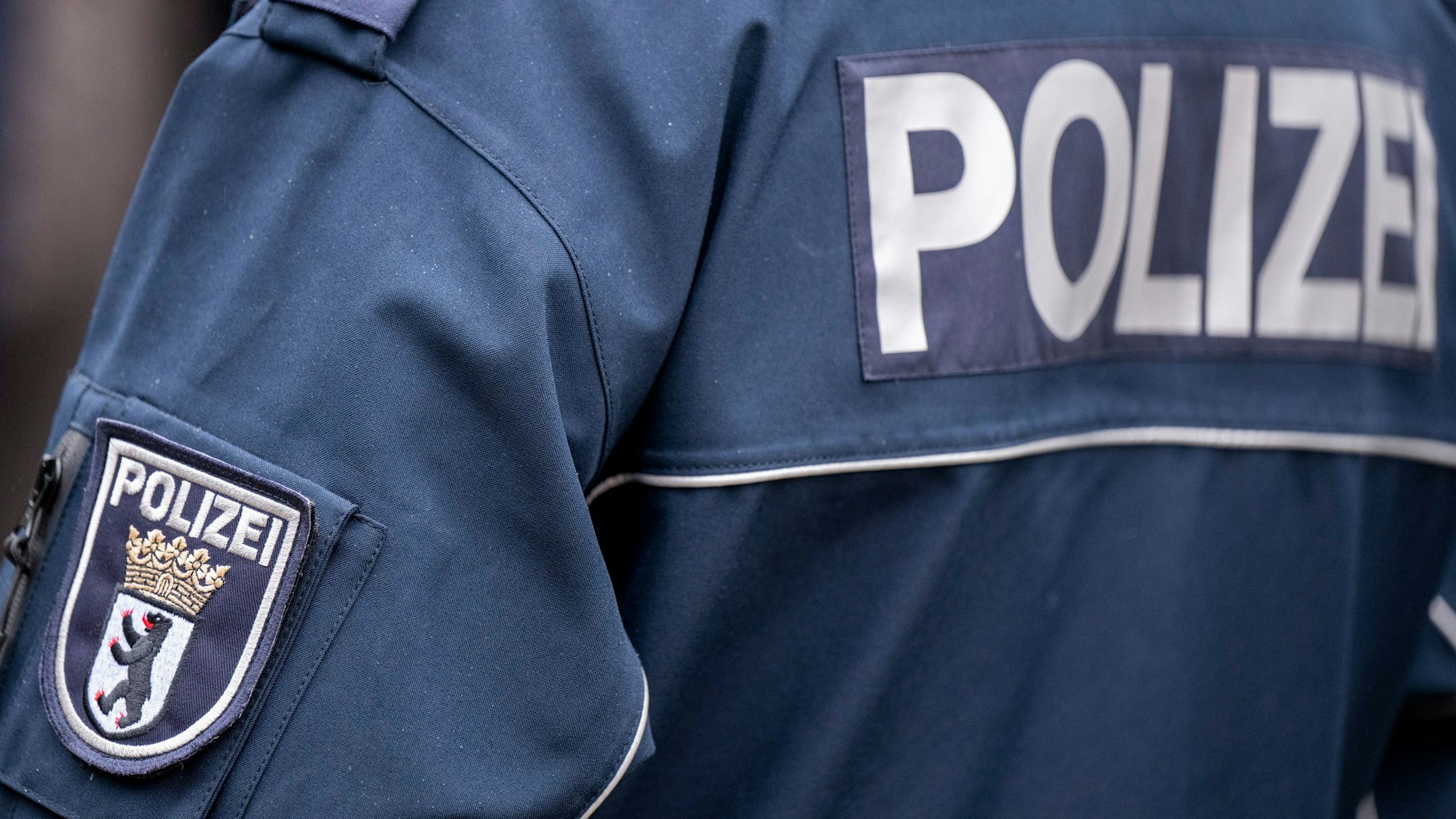Die Aufschrift Polizei und der Wappen von Berlin auf der Uniform eines Polizeibeamten