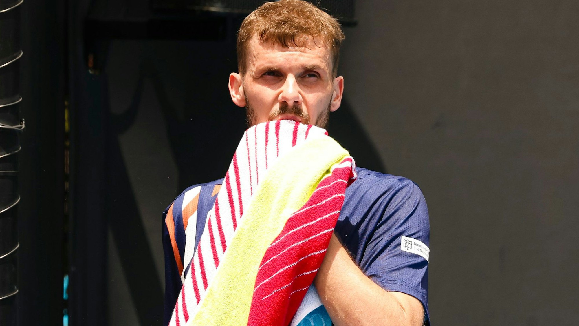 Tennisprofi Oscar Otte wischt sich mit einem Handtuch durchs Gesicht.