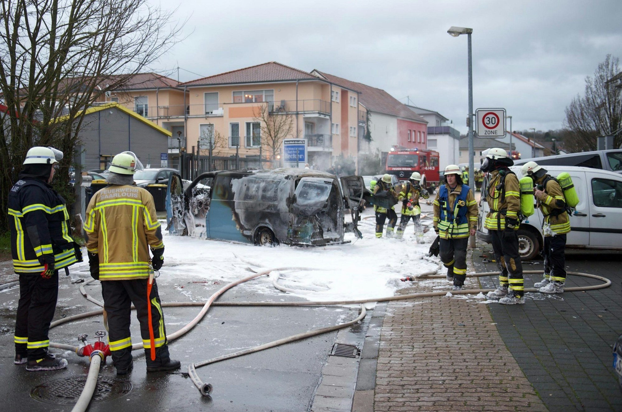 Einsatzkräfte stehen um einen gelöschten Geldtransporter.