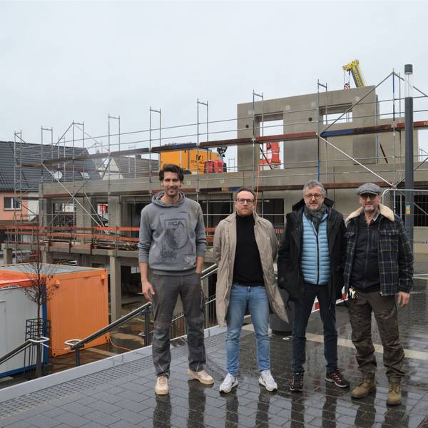 Vier Männer stehen vor der Baustelle eines neuen Hauses am Kaller Bahnhof.