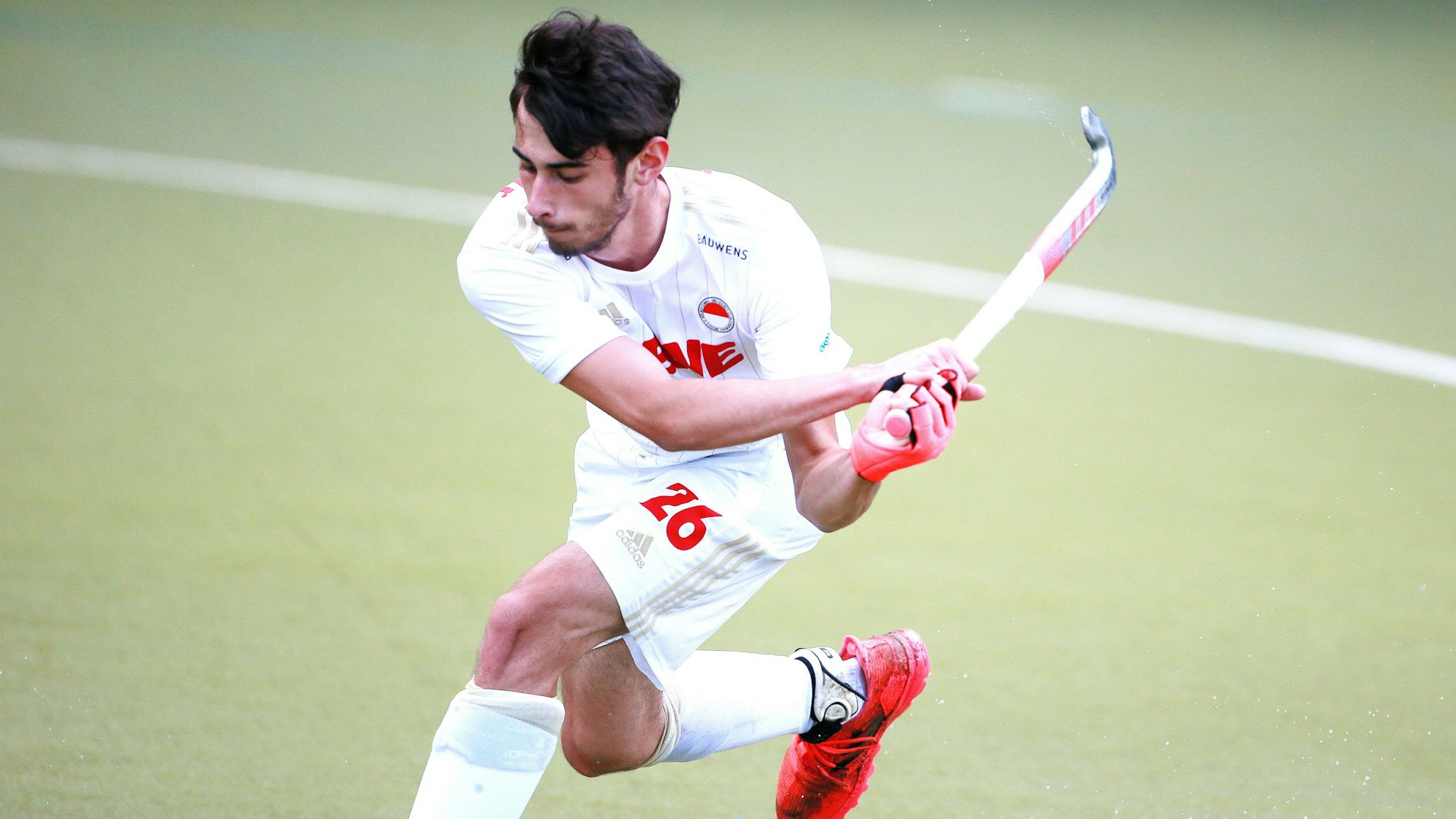 Ein Hockeyspieler holt mit seinem Schläger zum Schuss aus.