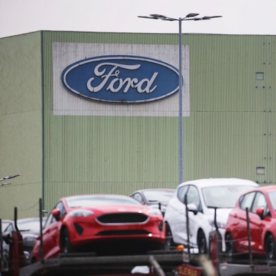Neu gebaute Autos stehen auf Lastwagen vor dem Ford Werk.