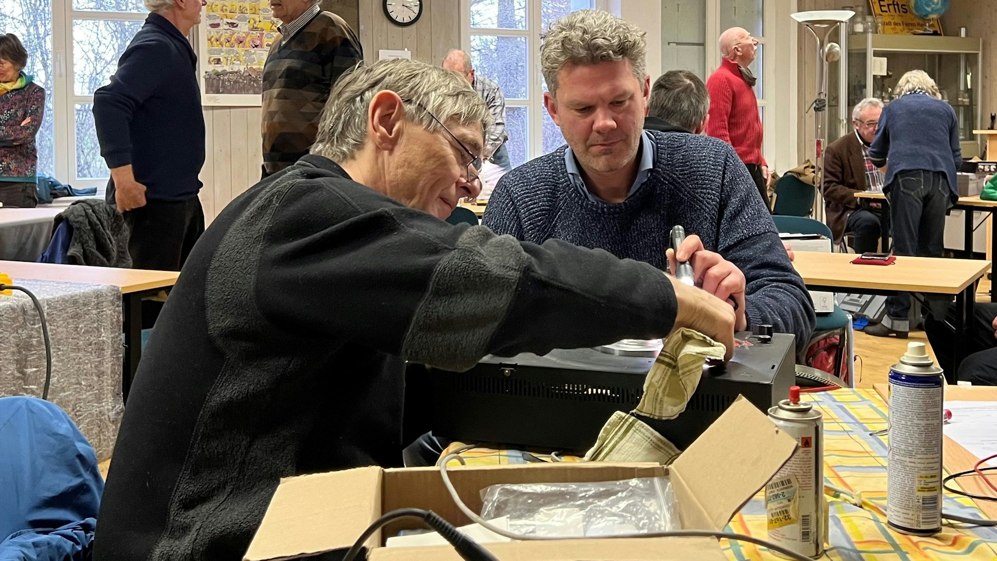 Zwei Männer reparieren einen alten Verstärker.