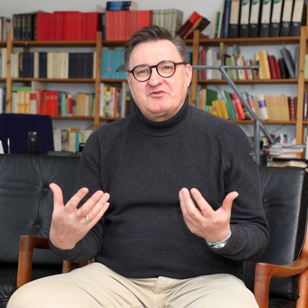 Norbert Hörter sitzt vor einer Bücherwand und gestikuliert.