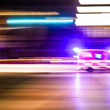 Ein Rettungsfahrzeug ist vor Tagesanbruch mit Blaulicht unterwegs (Aufnahme mit Mitzieheffekt).