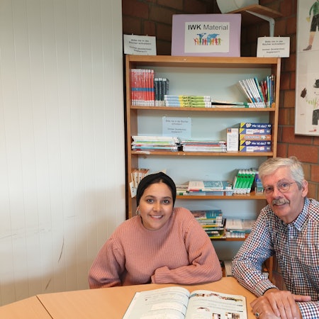Harald Raab und eine Jugendliche sitzen an einem Tisch vor einem Buch.