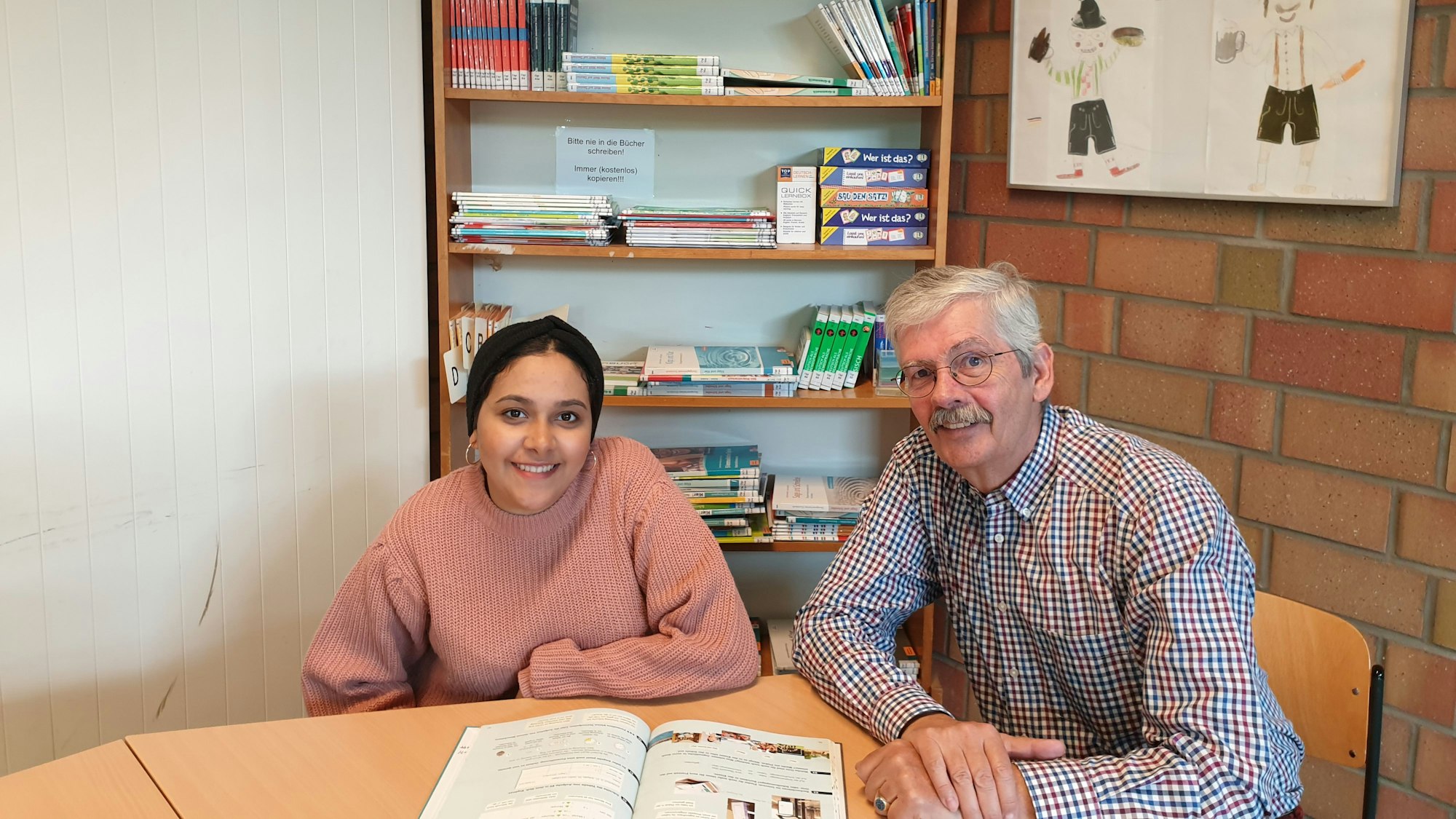 Harald Raab und eine Jugendliche sitzen an einem Tisch vor einem Buch.