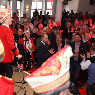 Alexander Pfister steht mit Krücken vor einem Mikro auf einer Karnevalsbühne.