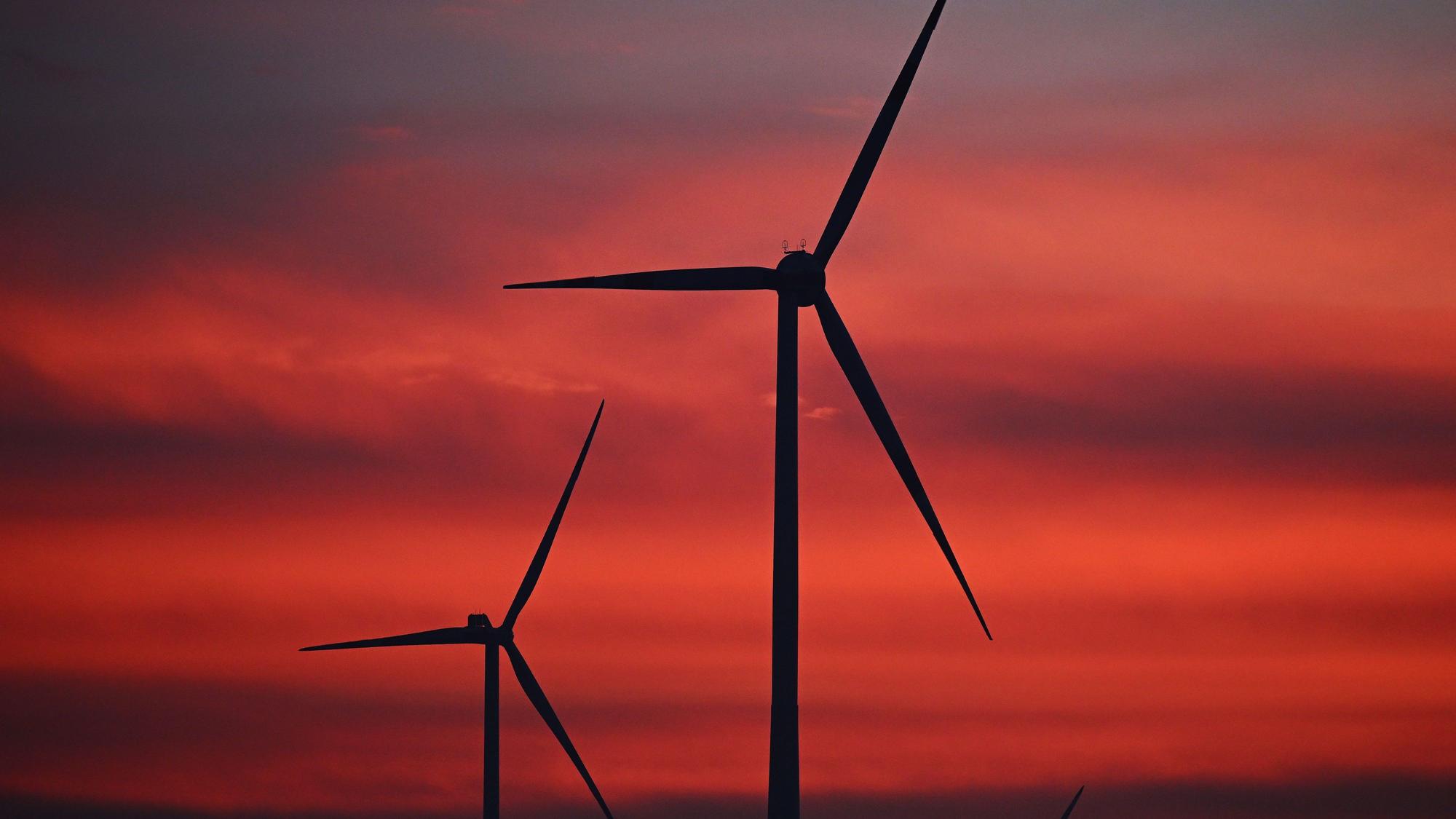 Windräder sind im Windpark Neudorf bei Sonnenaufgang zu sehen.